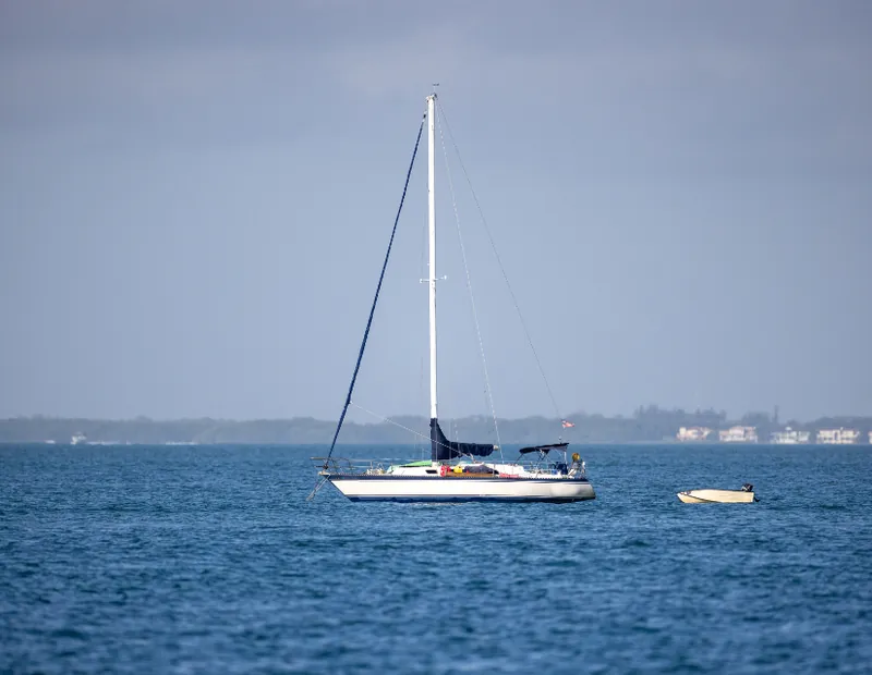 Sailing boat with cream sails on calm blue water